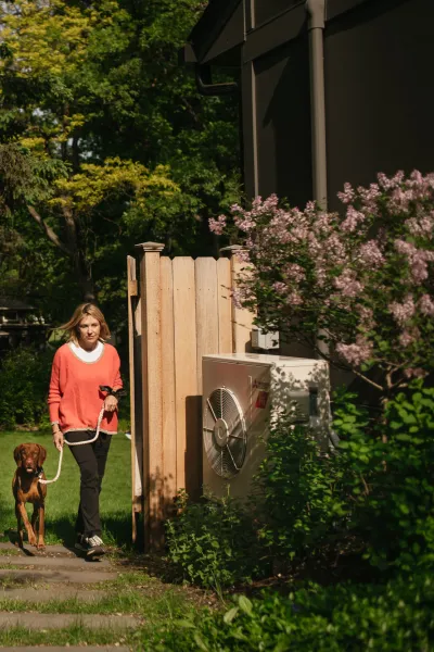 Heat pump installed outside of home with a homeowner and her dog. 